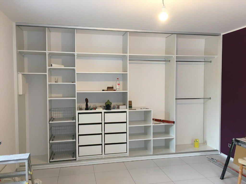 Montaż dużej białej szafy zabudowanej w trakcie prac